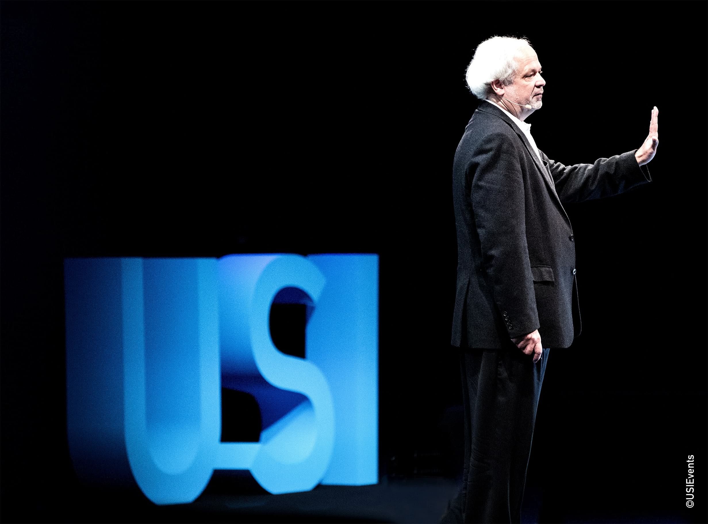 Juan Enriquez sur la scène de la conférence USI durant son talk